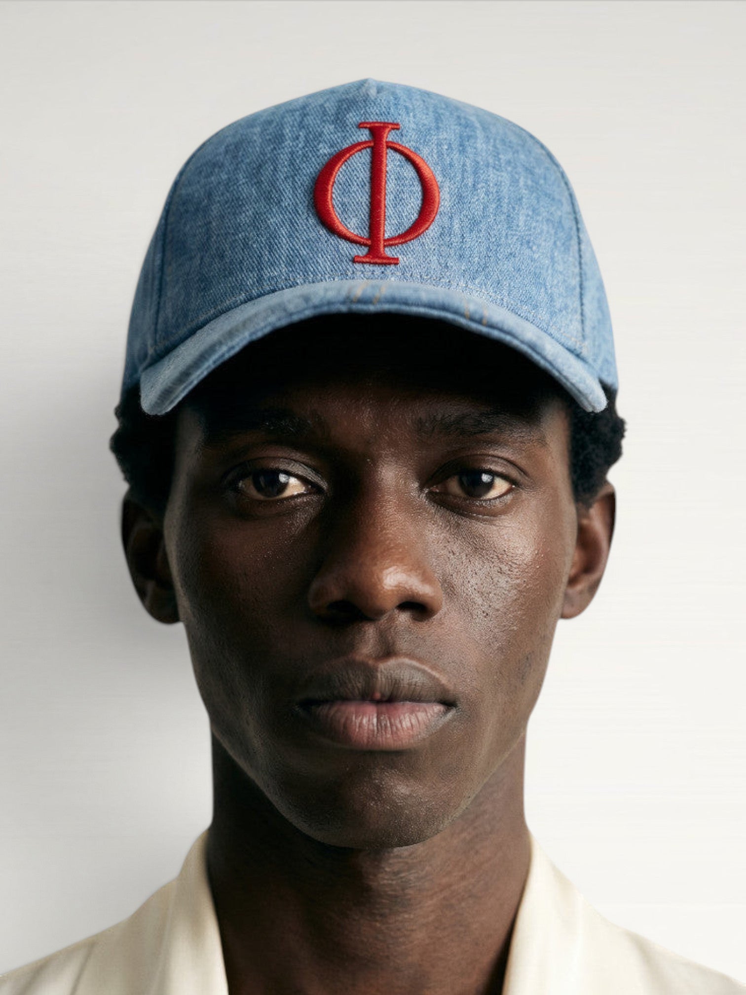 ILIMITO light wash denim baseball cap with red embroidered logo emblem, curved brim, adjustable strap. Unisex fit.