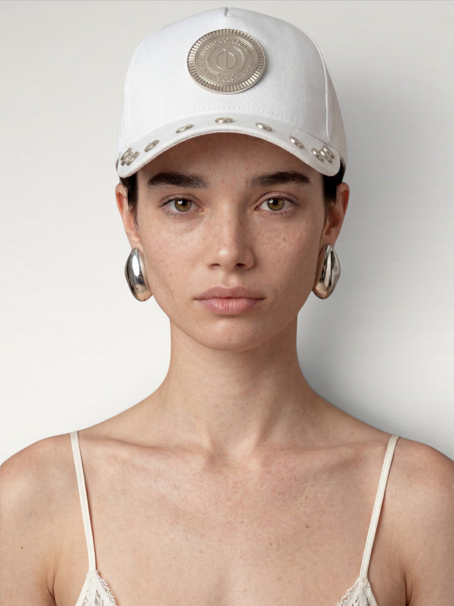ILIMITO white cotton blend cap with silver medallion detail and accents on the visor. Unisex, adjustable fit.