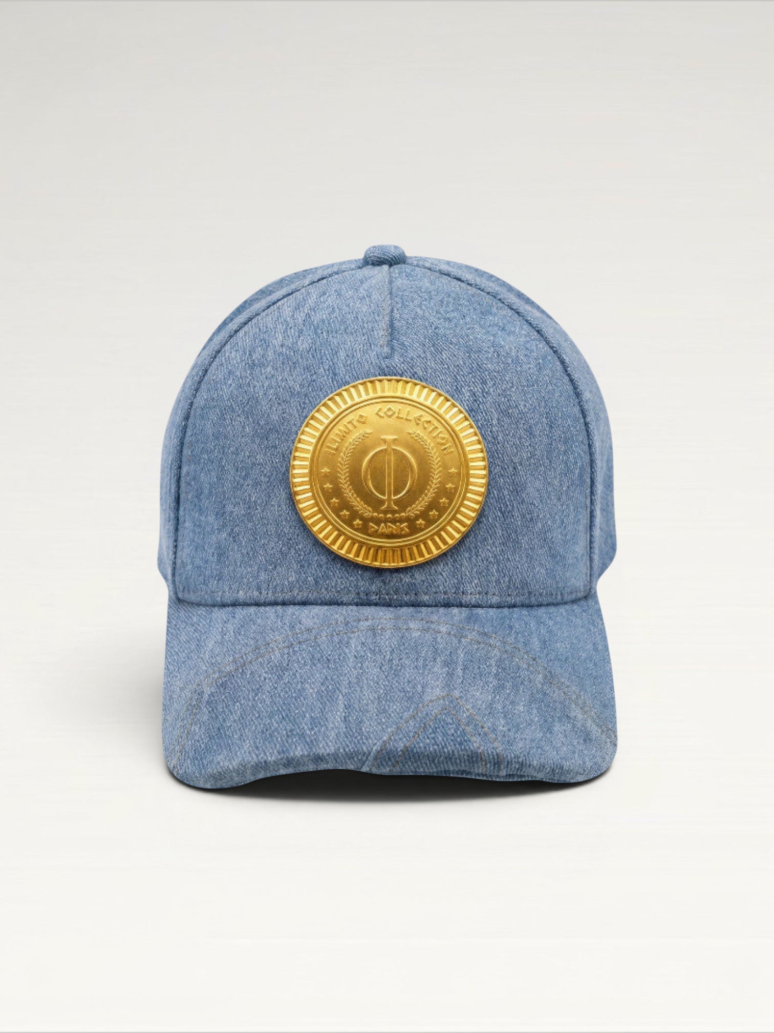 ILIMITO light blue denim baseball cap with curved brim and a central gold medallion emblem. Unisex fit.