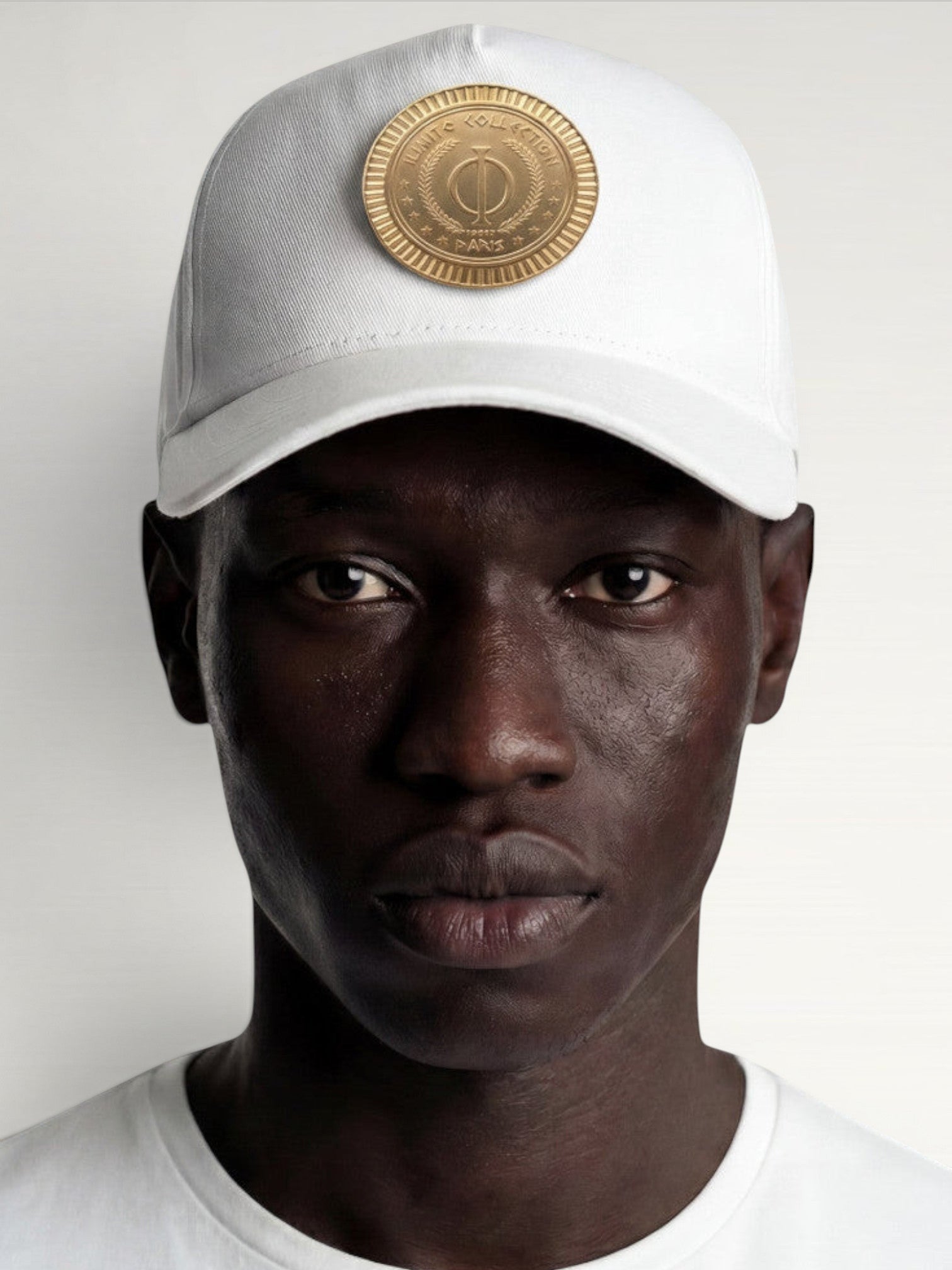 ILIMITO white cotton blend baseball cap with curved brim and gold medallion emblem. Unisex fit, adjustable closure.